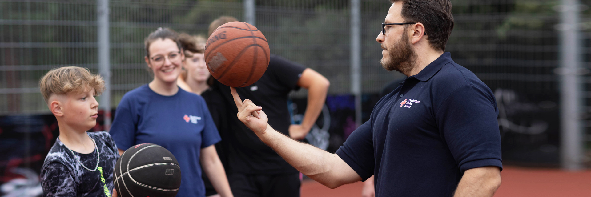 Integrationshelfer spielt mit Kind Basketball