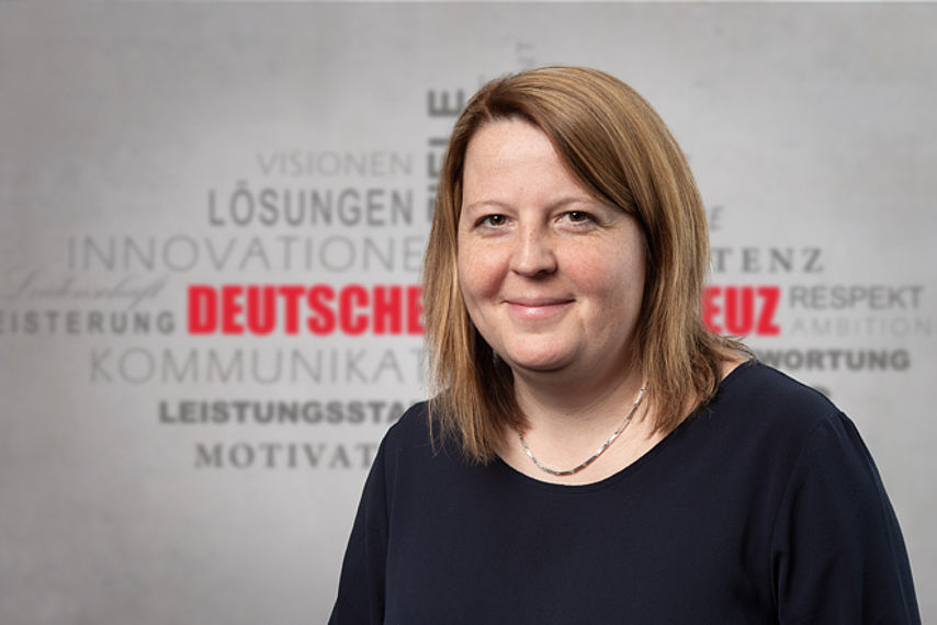 Claudia Janik Mitarbeiterfoto vor Rotkreuz-Hintergrund