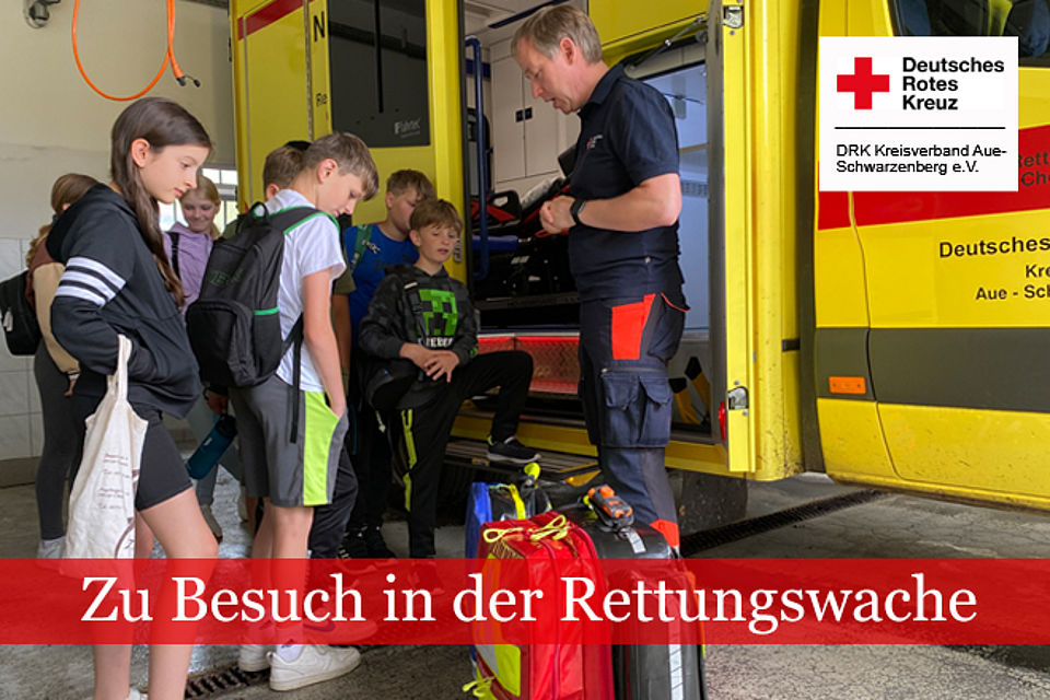 Schülerinnen und Schüler stehen mit einem Praxisanleiter vom Rettungsdienst vor einem RTW