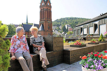 Zwei Frauen sitzen auf der Dachterasse mit Blick auf die Rote Kirche Aue